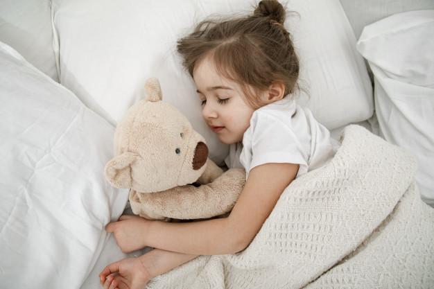 cute-little-girl-is-sleeping-bed-with-teddy-bear-toy_169016-4225